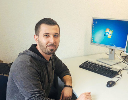 Ein junger Mann sitzt am Schreibtisch.