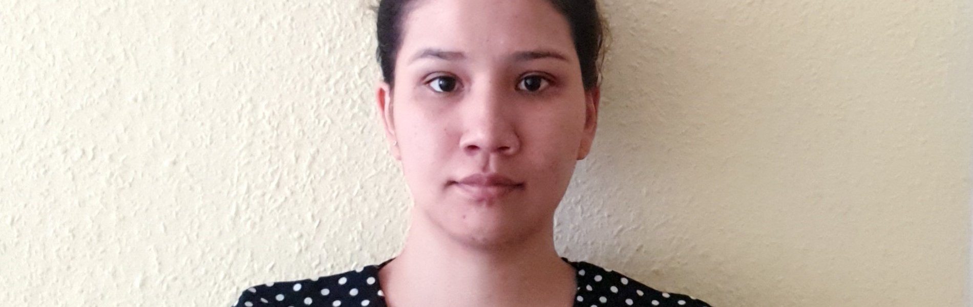 Eine junge Frau steht vor einer weißen Wand