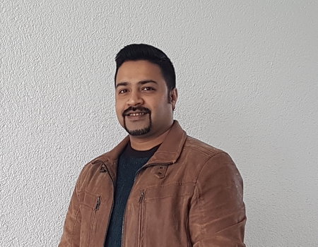 Ein junger Mann steht vor einer weißen Wand.