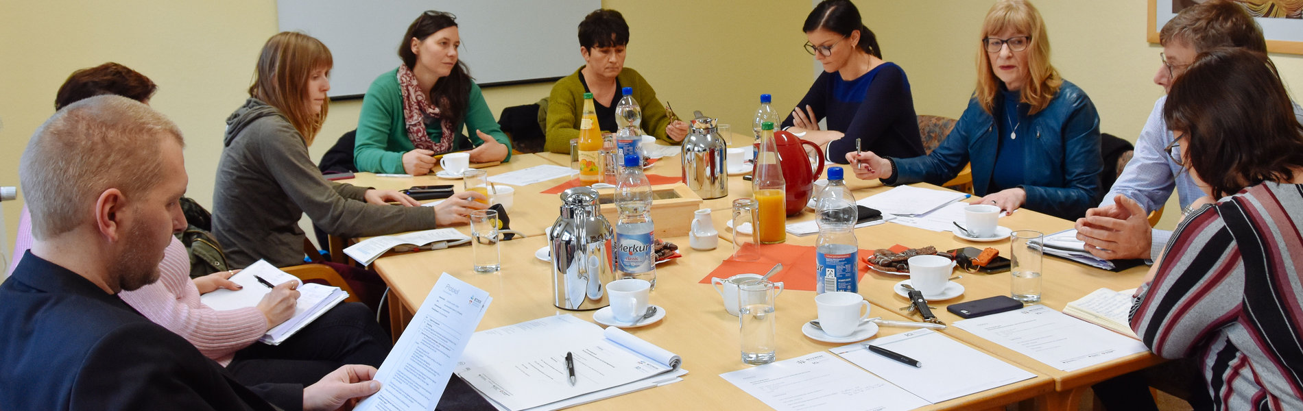 Eine Gruppe von Menschen sitzt um einen Tisch herum und arbeitet.