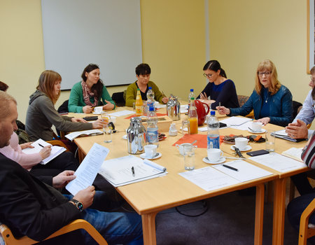 Eine Gruppe von Menschen sitzt um einen Tisch herum und arbeitet.