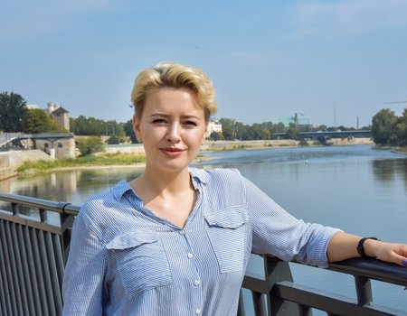 Eine junge blonde Frau steht an der Elbe.