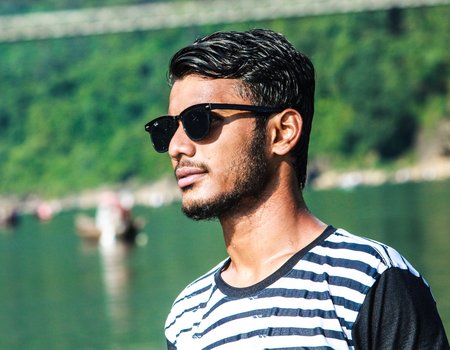 Ein junger Mann mit Sonnenbrille schaut zur Seite.