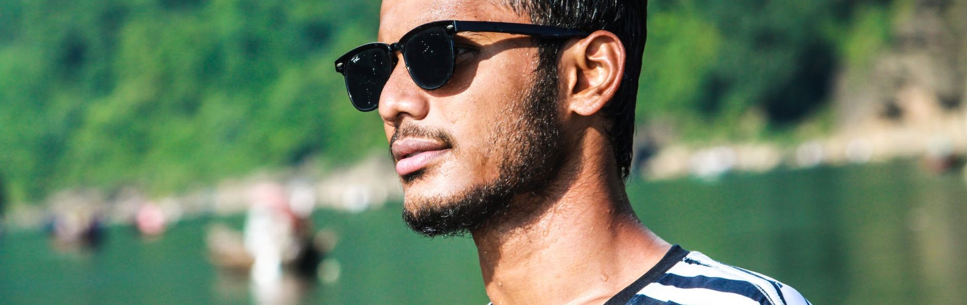 Ein junger Mann mit Sonnenbrille schaut zur Seite.