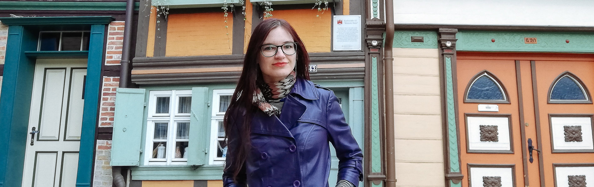 Eine junge Frau steht vor Fachwerkhäusern