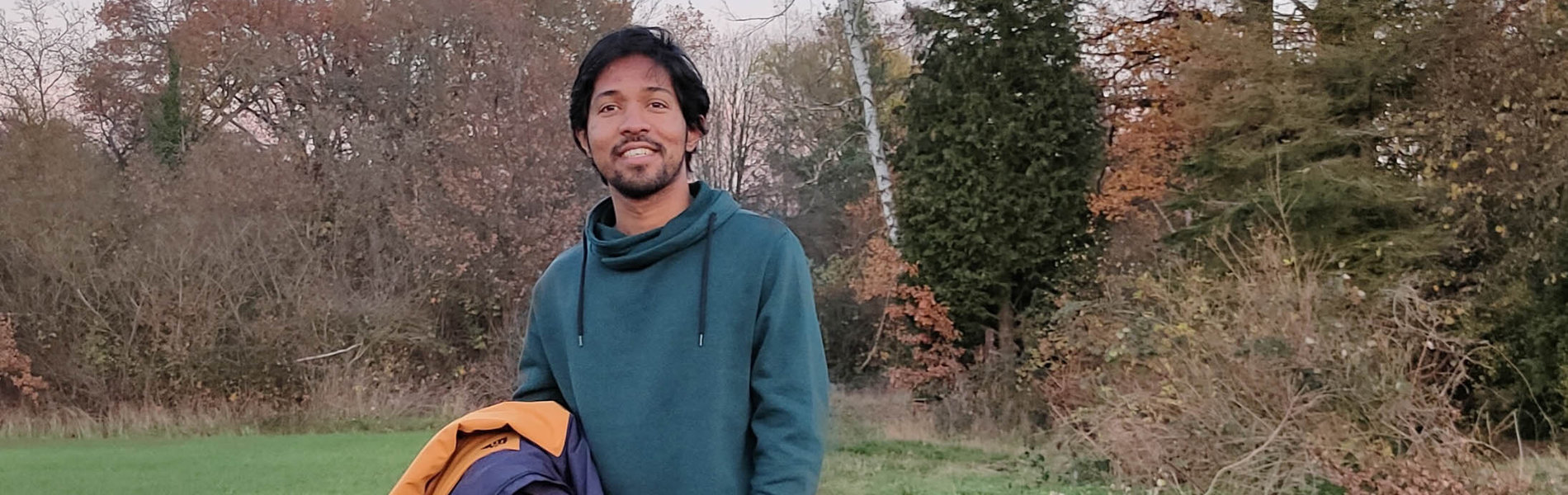 Ein junger Mann aus Indien steht auf einem Waldweg.