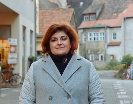 Eine junge Frau steht im Wintermantel auf der Straße.