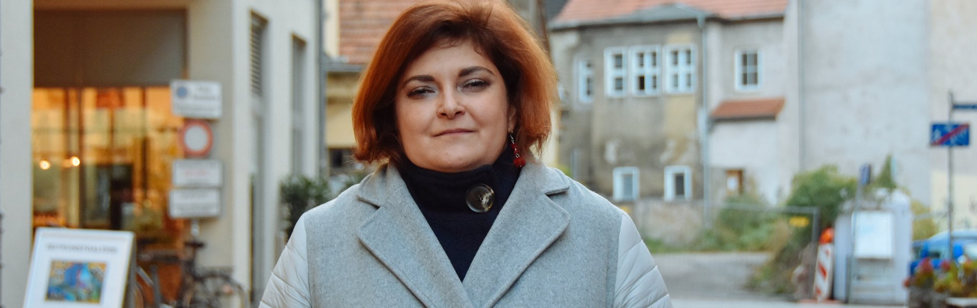 Eine junge Frau steht im Wintermantel auf der Straße.