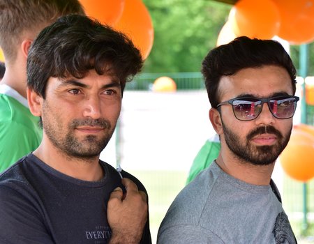 Zwei zugewanderte Mitspieler schauen erwartungsfroh in die Kamera.