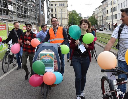 Eine Gruppe von Menschen mit Rädern und bunten Luftballons auf der Straße.