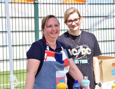 Elena Schmidt, Mitarbeiterin der Caritas im Angebot IQ Netzwerk, steht mit der Caritas-Praktikantin Luisa am Grill. Man kann die leckeren Würstchen fast riechen!
