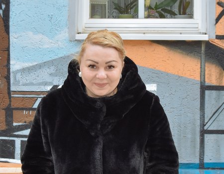 Eine junge Frau mit blonden Haaren grinst frech in die Kamera.