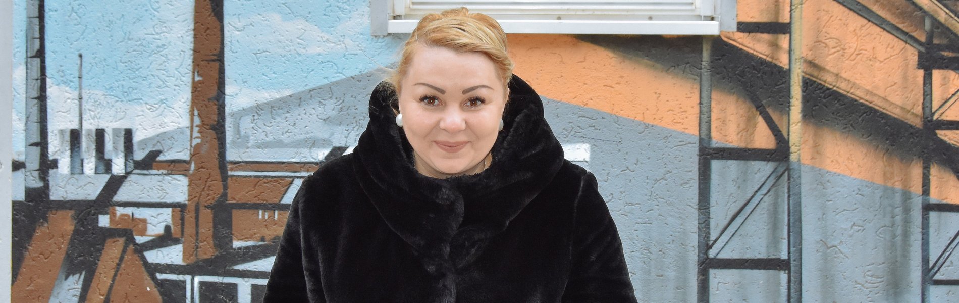 Eine junge Frau mit blonden Haaren grinst frech in die Kamera.