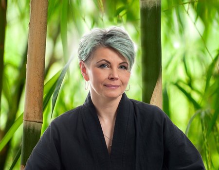 Eine blonde Frau sitzt im Schneidersitz.