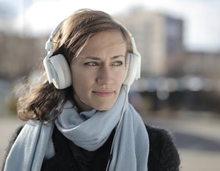 Eine junge Frau schaut ernst und trägt Kopfhörer
