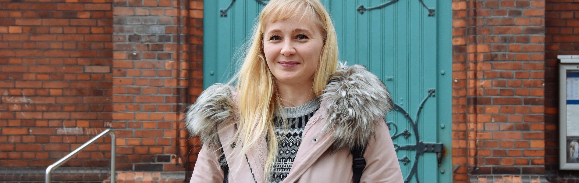 Ein junge blonde Frau steht vor einer Kirche.