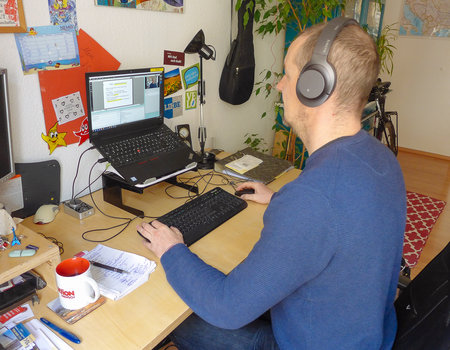 Der Dozent sitzt vor seinem Laptop