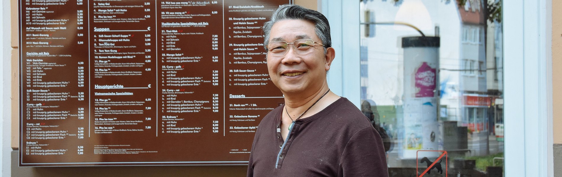 Ein ältere Mann steht vor seinem asiatischen Restaurant.