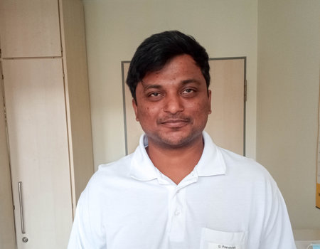 Ein Mann aus Indien steht in einem Raum und trägt eine Ärzteuniform.