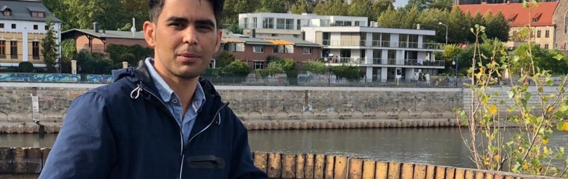 Ein junger Mann steht am Ufer der Elbe.