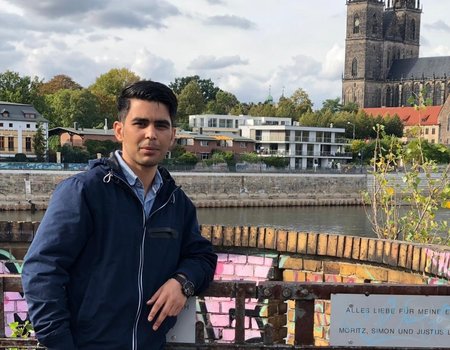 Ein junger Mann steht am Ufer der Elbe.