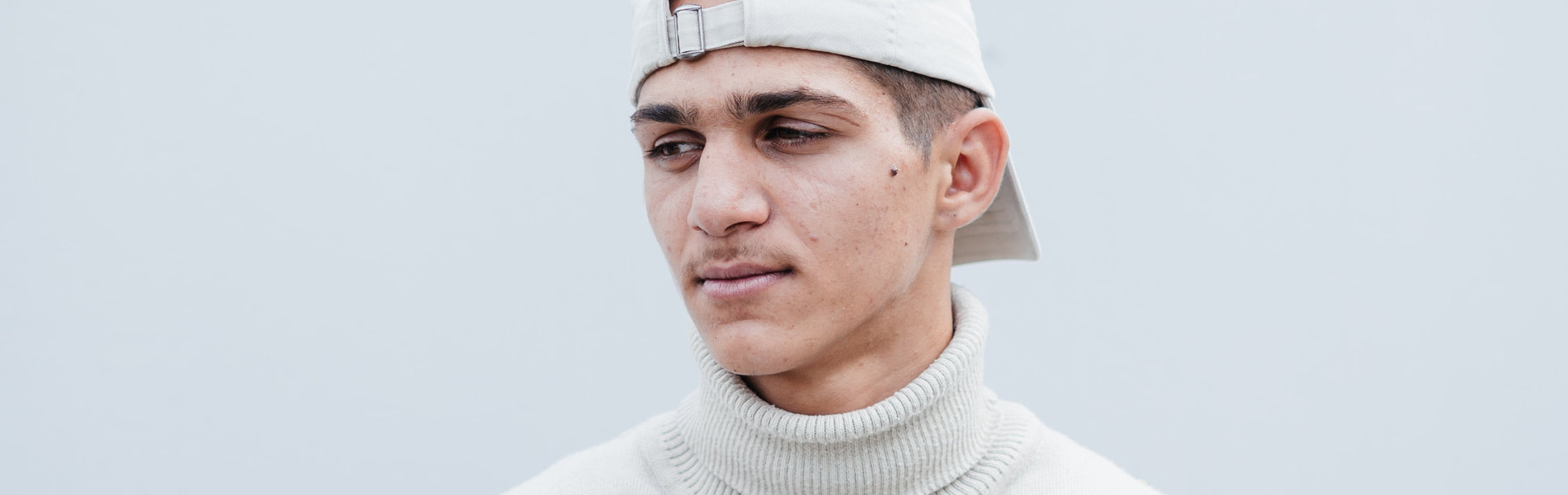 Ein junger Mann mit weißer Cap auf dem Kopf.