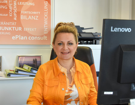 Eine blonde Frau sitzt vor einem Computer.