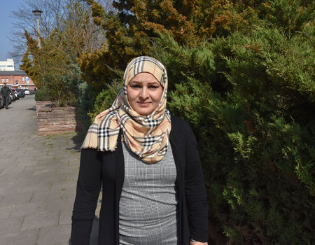 Eine junge Frau mit Kopftuch schaut freundlich in die Kamera. Die Sonne blendet sie etwas.