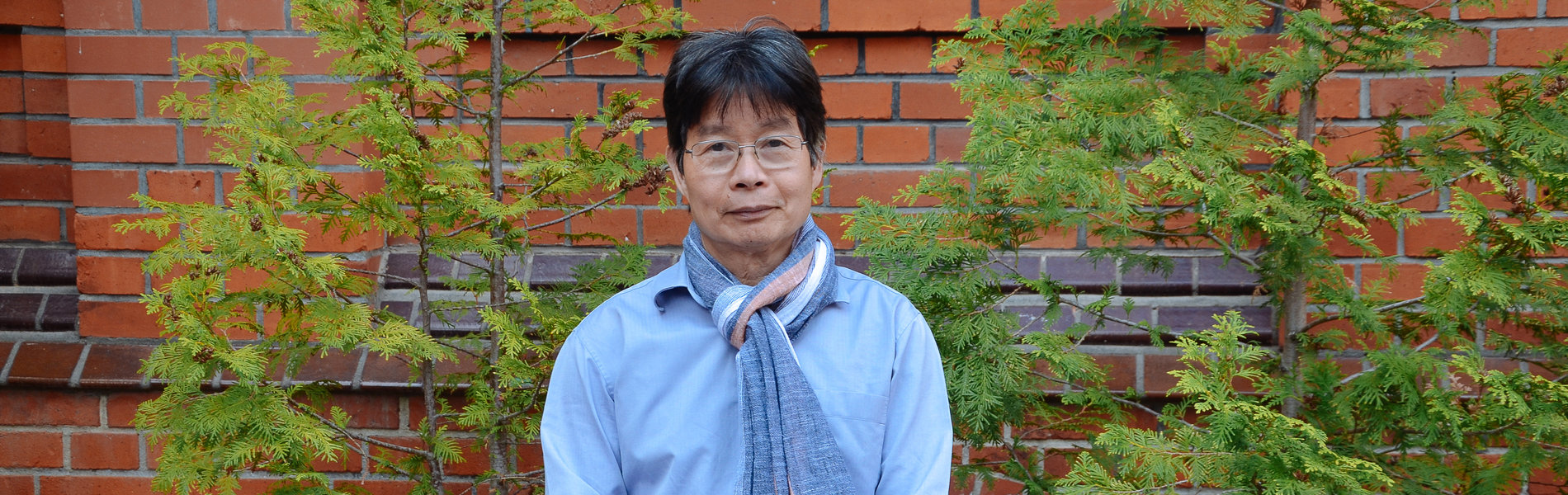Ein älter Herr aus Vietnam steht vor einer Mauer.